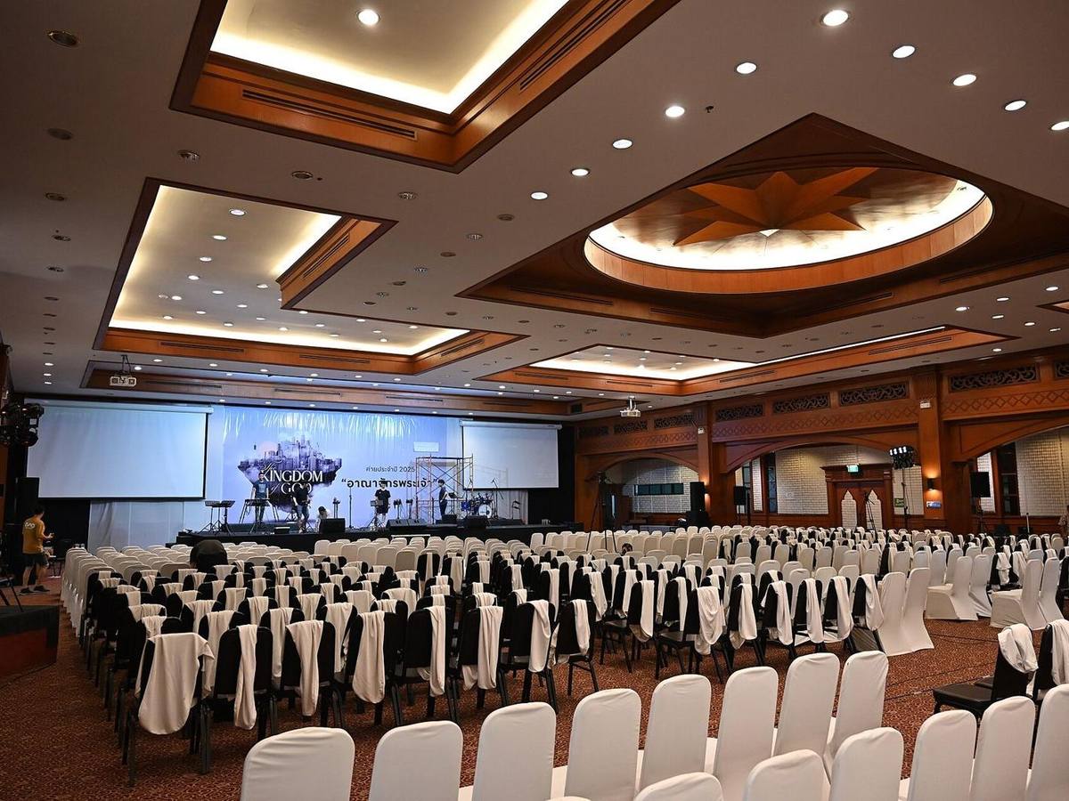 A conference hall set with rows of chairs facing a stage